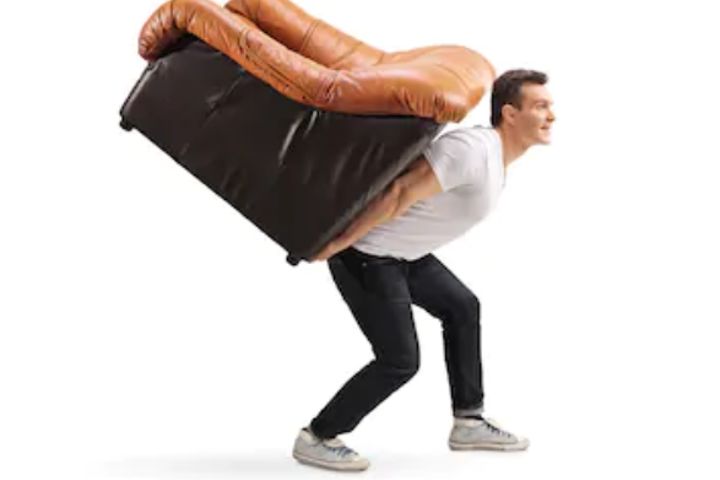 man carrying an armchair on his back