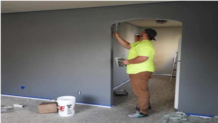 man painting walls and interior doorway in dark color