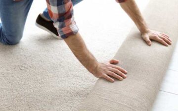 unrolling a new carpet over a floor