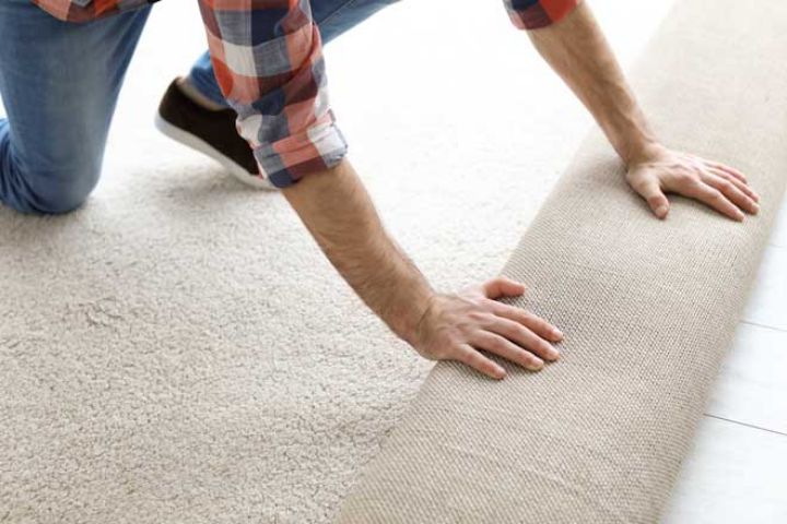 unrolling a new carpet over a floor