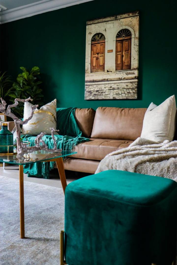 room with green wall, green blanket on sofa, and green ottoman