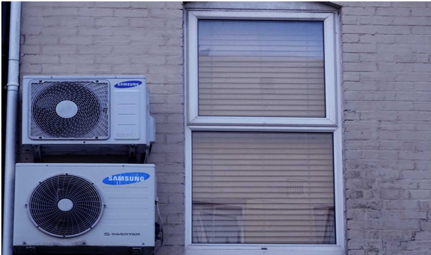 air conditioning condensers on outside wall next to a window