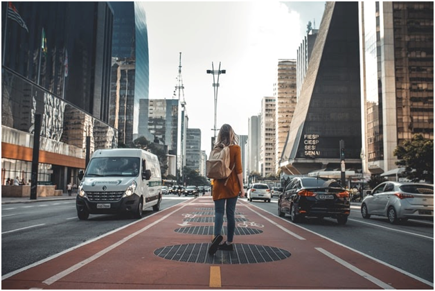 young woman walking in the middle of a busy street in a city