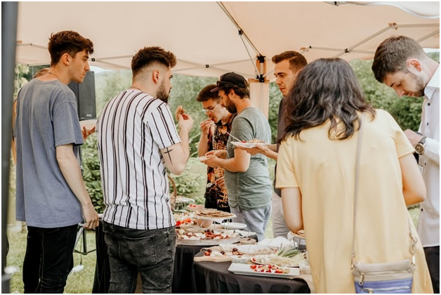 young people standing around food tables