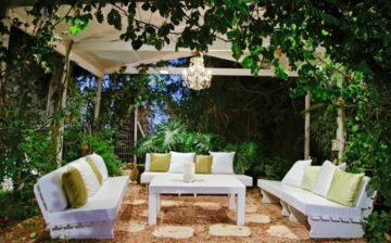 covered lighted patio with furniture and surrounded by trees