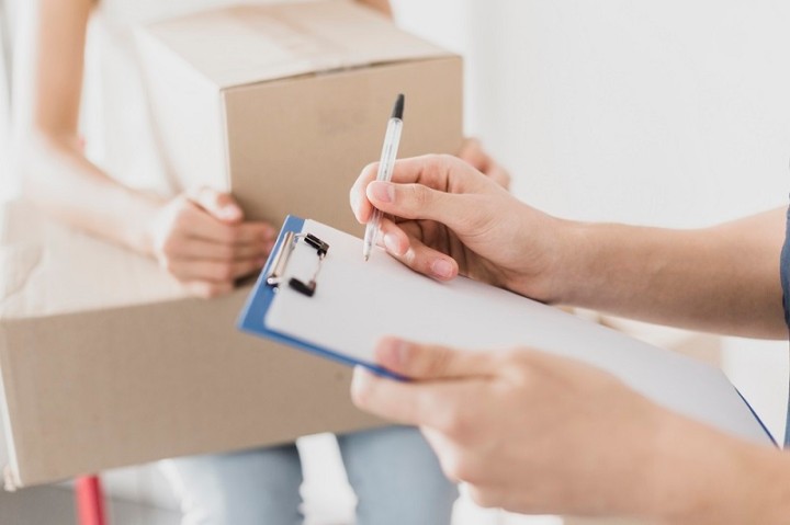 man with clipboard and woman seated holding boxes