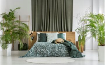 bed with curtain behind and potted plants on each side