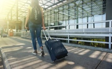 young woman with backpack pulling luggage