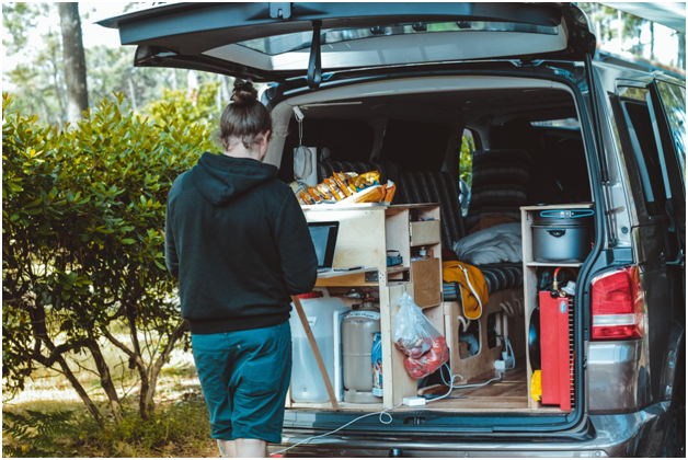 solo traveler standing at back of well-stocked vehicle