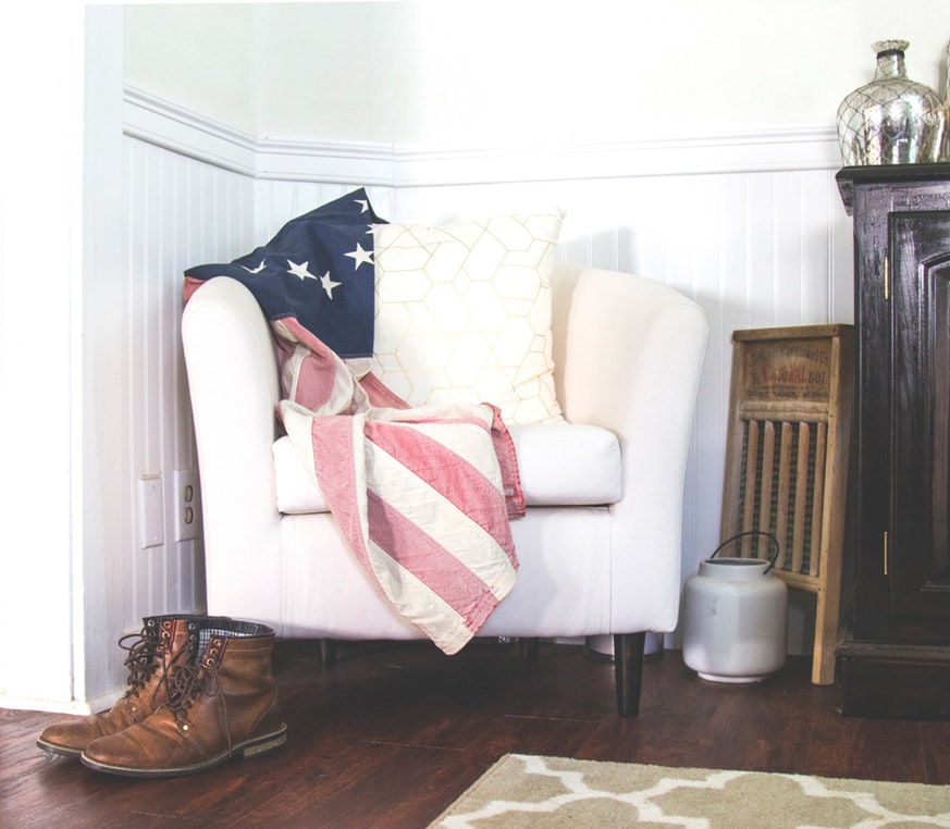 pair of boots next to a lounge chair with a flag draped on it