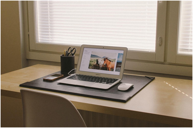 laptop on desk in front of a window