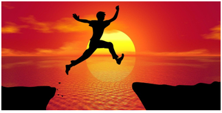 silhouette of person jumping across a gap with sun setting on ocean in background