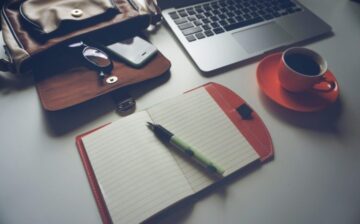 briefcase, laptop, notebook with pen, and coffee cup