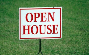 Open house sign nailed to the grass.
