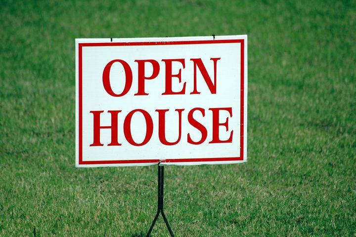 Open house sign nailed to the grass.
