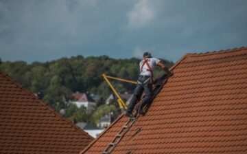 man laying shingles on a roof
