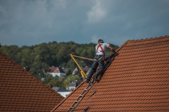 man laying shingles on a roof