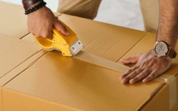 man sealing a moving box with packing tape