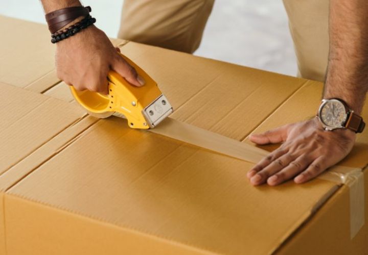 man sealing a moving box with packing tape