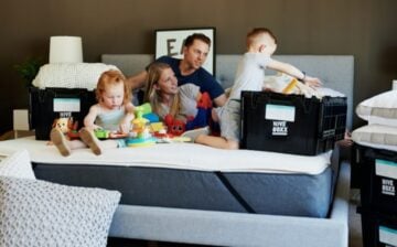 couple with young kids playing on a bed