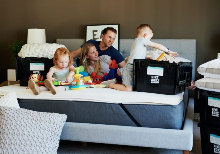 couple with young kids playing on a bed