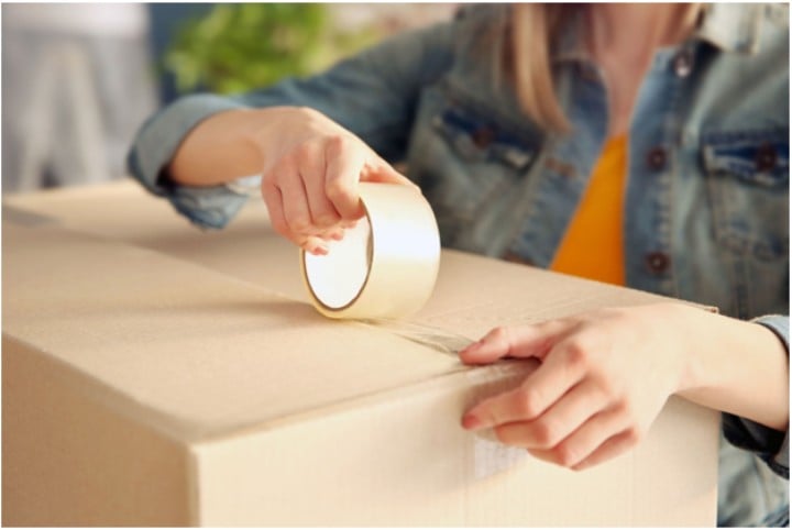 woman sealing a packing box