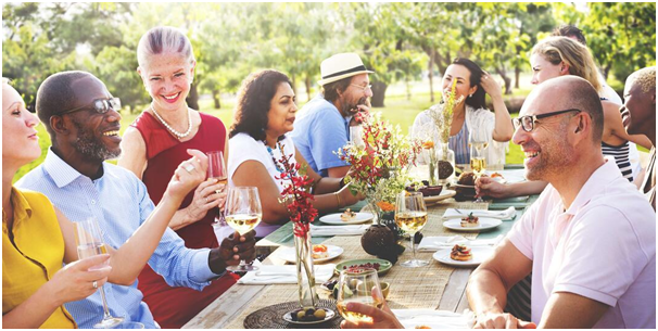 neighbors sharing dessert and wine at an outdoor picnic table