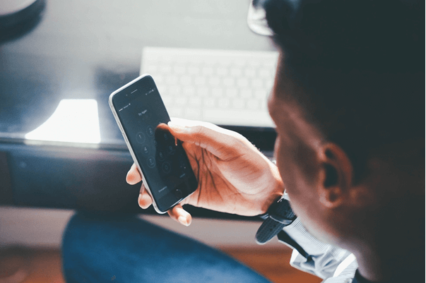 man sitting at desk looking at smartphone