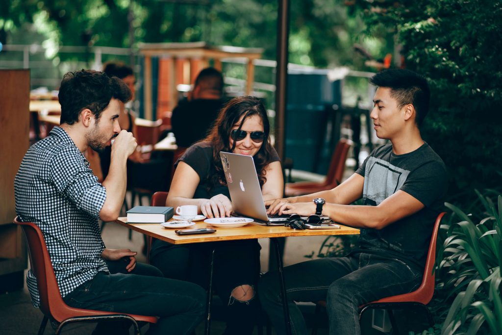 young adults sitting at outdoor table in coffee shop
