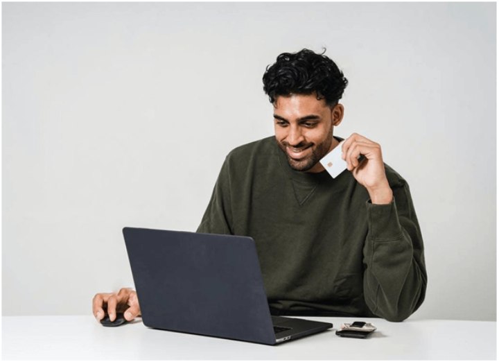 young man at laptop holding credit card