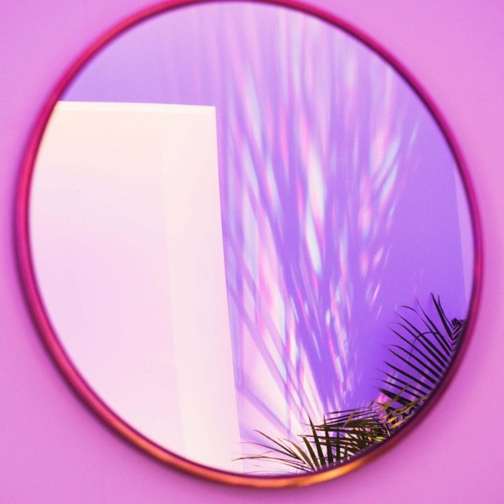 large mirror with purple frame hung on purple wall