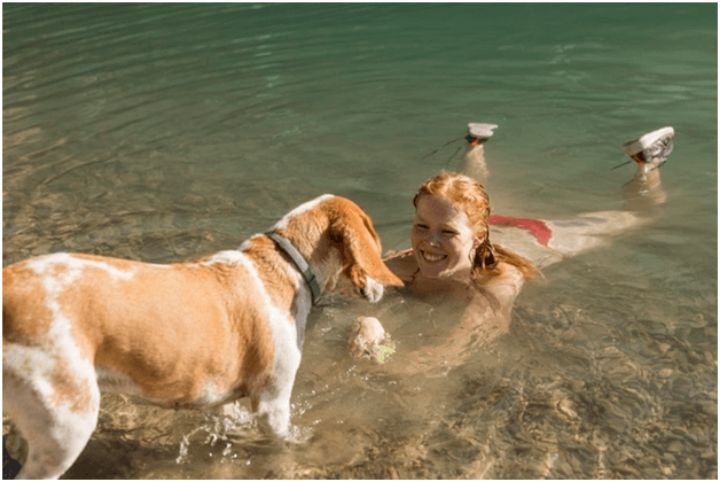 woman playing in the water with a dog
