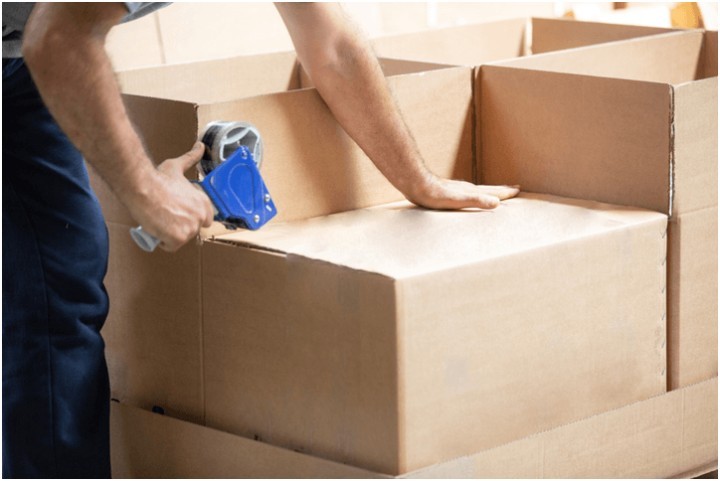man sealing a moving box