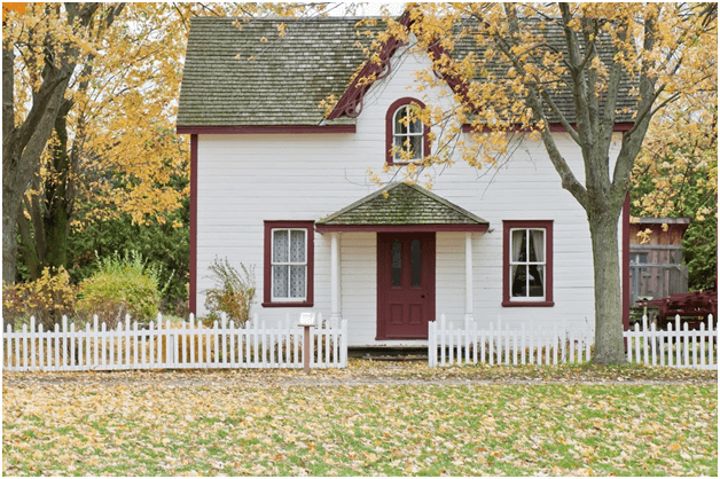 house in wooded area with white picket fence