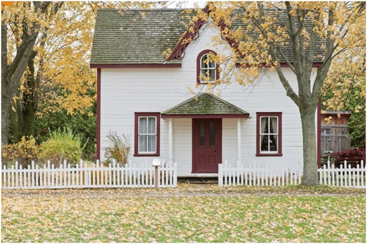 house in wooded area with white picket fence