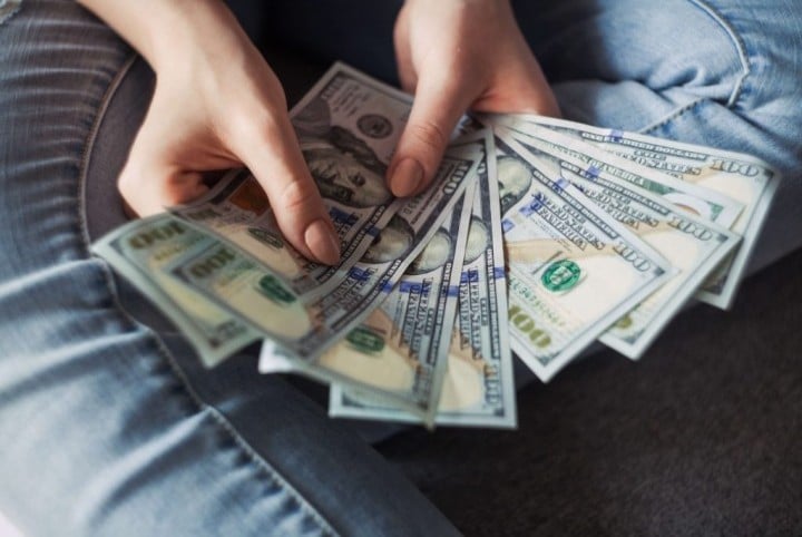 woman holding various currency bills