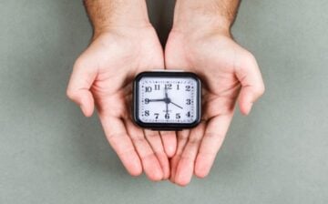 pair of hands holding a clock