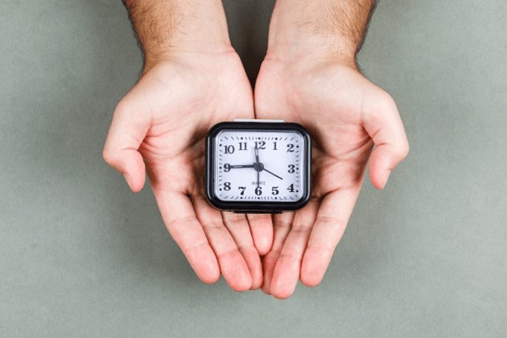 pair of hands holding a clock