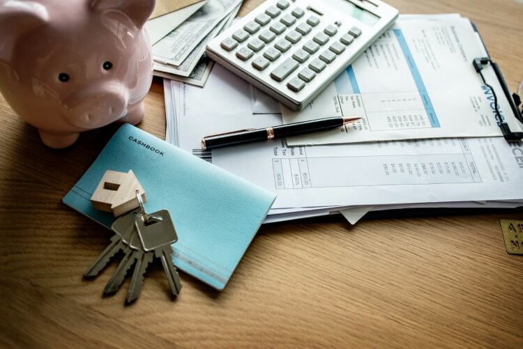 financial paperwork with keys and piggy bank next to it
