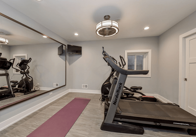 home gym with elliptical machine, treadmill, TV, and large mirror