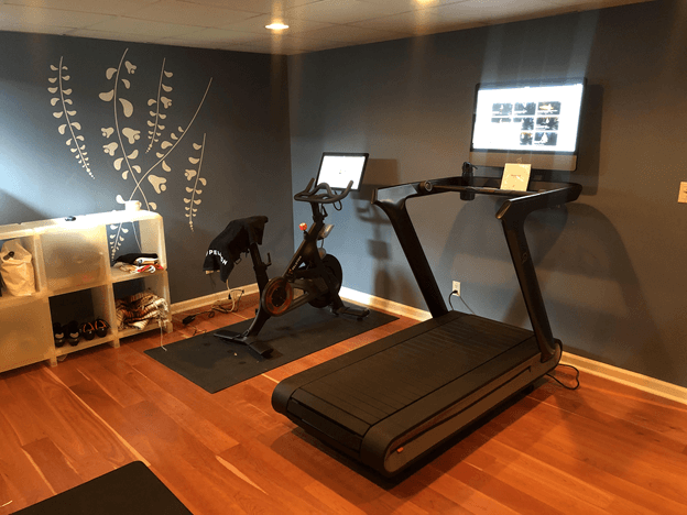 home gym with stationary bike, treadmill, TV, and clothes rack