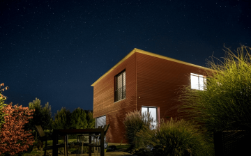 Wooden house set against a beautiful clear night sky surrounded by trees