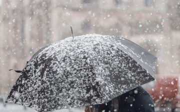 Person out walking on a snowy day with an umbrella thinking about moving house