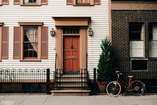 townhome with red front door leading out to a sidewalk