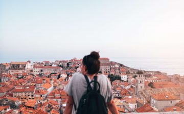 Adventurous student looking across a city from above ready to travel and explore