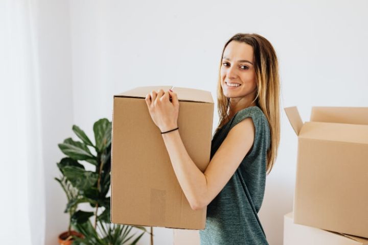 woman holding moving box in new house