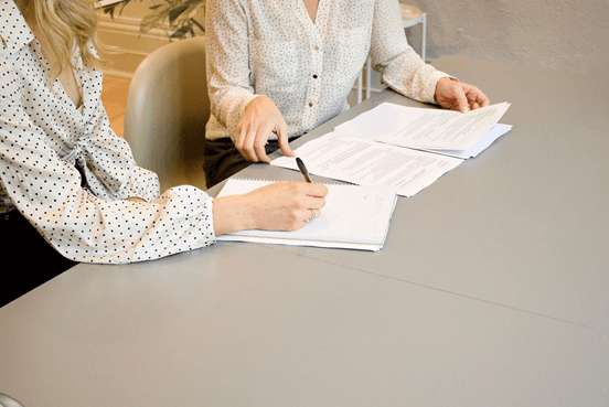 two women sitting at a table reviewing documents