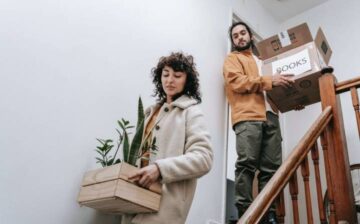 couple carrying moving boxes down stairs