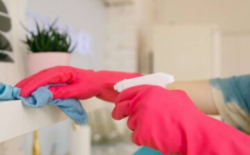 woman with gloves cleaning shelves