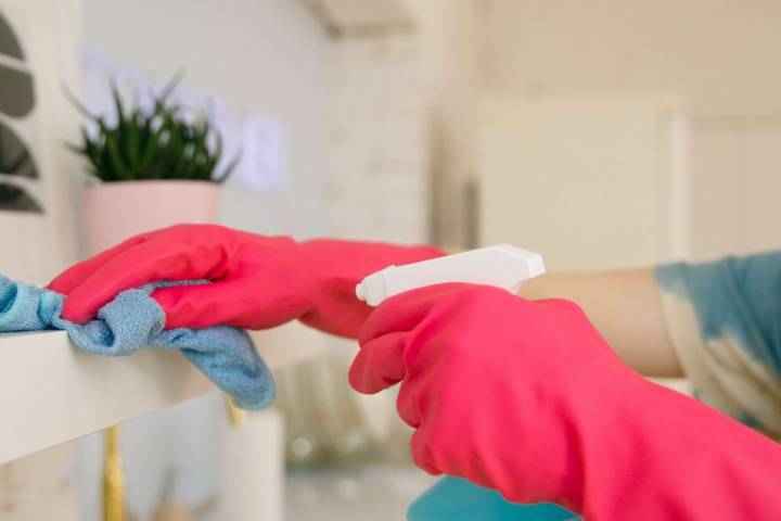 woman with gloves cleaning shelves